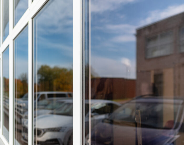 Office building or apartment house with cars parking reflection on a cloudy summer day.Business background.Selective focus.